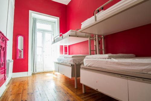 Safestay Lisbon Bairro Alto في لشبونة: غرفة بها ثلاثة أسرة بطابقين وجدار احمر