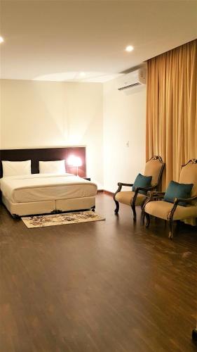 a bedroom with a bed and two chairs at Towlan Al Rawdah تولان للشقق المخدومة فرع الروضة in Riyadh
