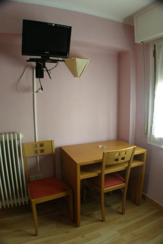 a room with a table and chairs and a tv on the wall at Hostal Restaurant Jose Luis in Trespaderne