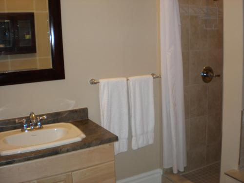 a bathroom with a sink and a shower with white towels at Spanish Bay Inn, CANADA in Sydney