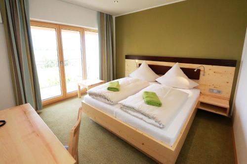 a bedroom with a bed with white sheets and green pillows at Gasthof Sempt in Spörerau
