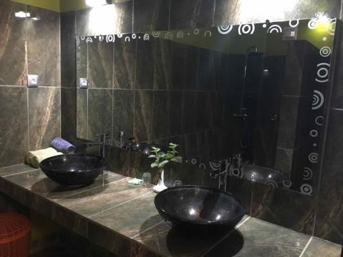 a bathroom with two black sinks and a mirror at Hotel de la Poste in Diego Suarez