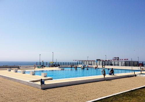 a large swimming pool next to the ocean at Parque de Campismo Orbitur Canidelo in Vila Nova de Gaia