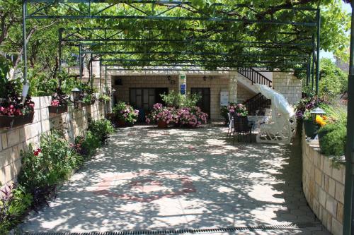 a garden walkway with flowers and a pergola at Apartments Sveti Anton in Orebić