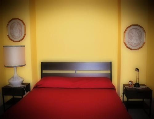 a bedroom with a red bed with yellow walls at Casa Vacanze Zia Titina in Trabia