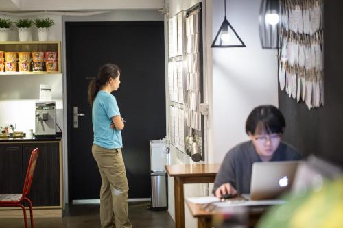 a woman standing at a table with a laptop at We Come Hostel in Taipei