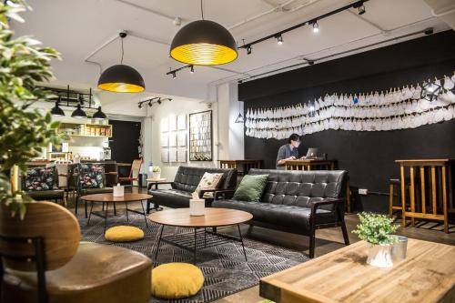 a bar with couches and tables and a man in the background at We Come Hostel in Taipei