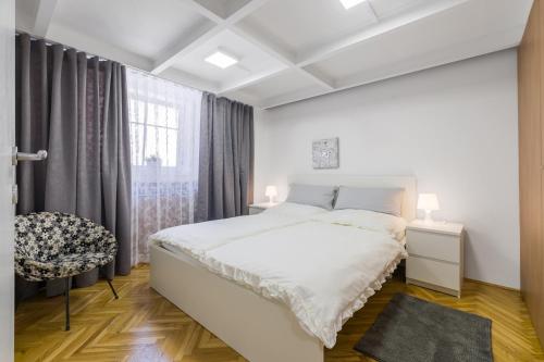 a white bedroom with a bed and a window at Duplex Urban Apartment in Ljubljana