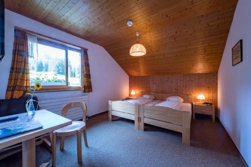 a bedroom with two beds and a table and a desk at Berghotel Sellamatt in Alt Sankt Johann