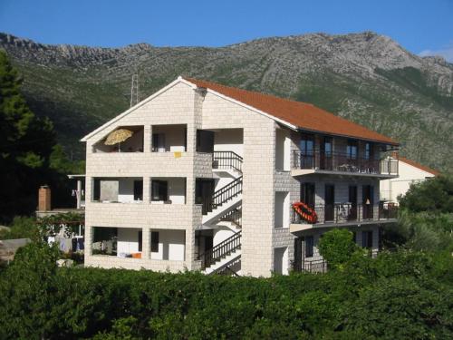 a white building with a mountain in the background at Apartments Sveti Anton in Orebić