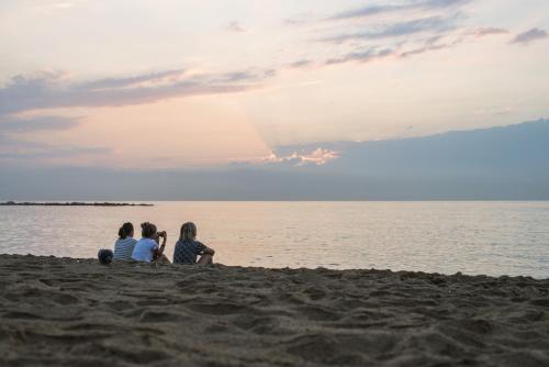 three girls sitting on the beach watching the sunset at Sea Hostel Barcelona in Barcelona