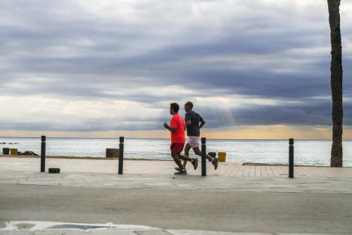 two people walking on the beach near the water at Sea Hostel Barcelona in Barcelona