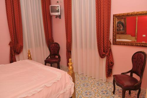 ein Schlafzimmer mit 2 Stühlen, einem Bett und einem Spiegel in der Unterkunft Albergo Roses in Paola