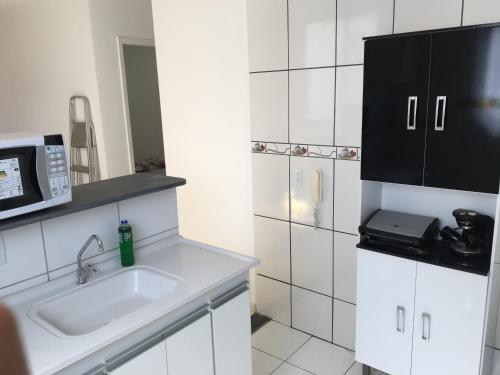 a white kitchen with a sink and a microwave at Apartamento-Excelente localização in Resende