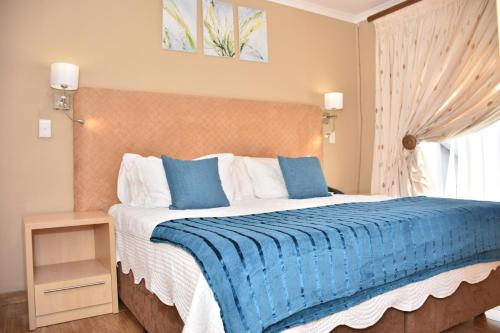 a bedroom with a large bed with a blue blanket at Homestay Travel Guest House in Roodepoort