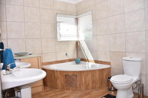 a bathroom with a tub and a toilet and a sink at Homestay Travel Guest House in Roodepoort