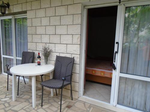 a patio with a white table and chairs and a window at Apartments Sveti Anton in Orebić