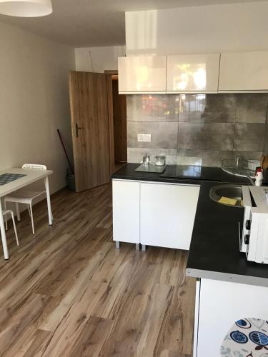 a kitchen with white cabinets and a wooden floor at Willa Wena in Ustka