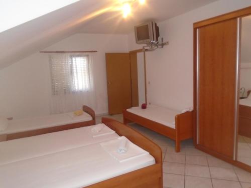 a small room with two beds and a tv at Apartments Sveti Anton in Orebić