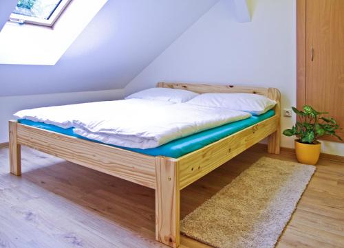 a wooden bed in a room with a window at Pension U pálenice in Hrabětice