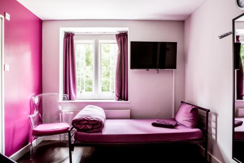 a pink room with a couch and a window at Safestay London Kensington Holland Park in London