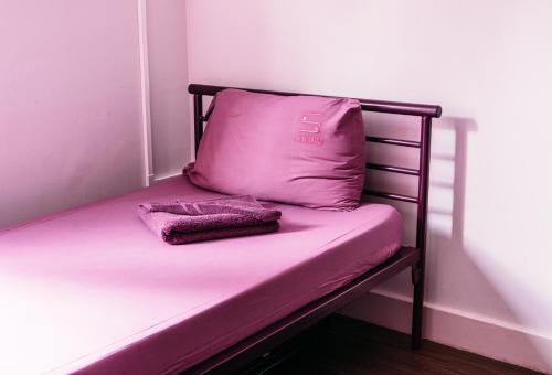 a bed with a pink pillow and towels on it at Safestay London Kensington Holland Park in London