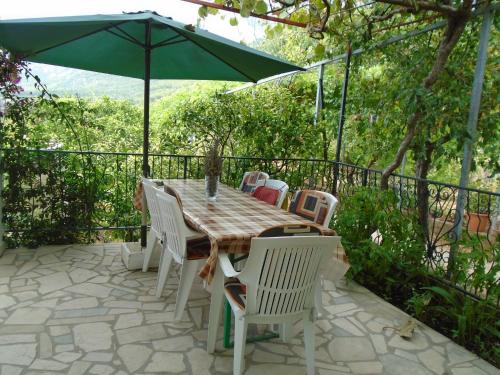 a table with chairs and an umbrella on a patio at Apartments Sveti Anton in Orebić