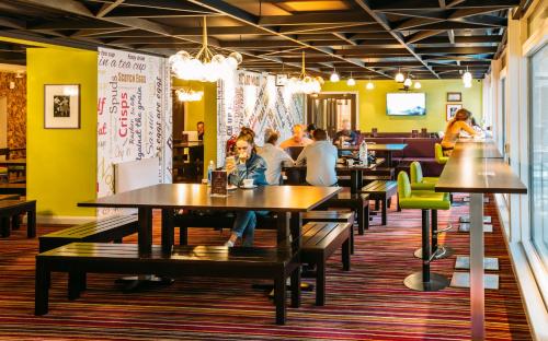 people sitting at tables in a restaurant with yellow walls at Safestay London Kensington Holland Park in London