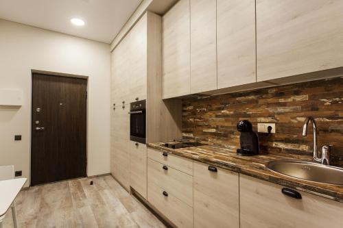 a kitchen with wooden cabinets and a sink at Old Town Trio Apartments in Vilnius