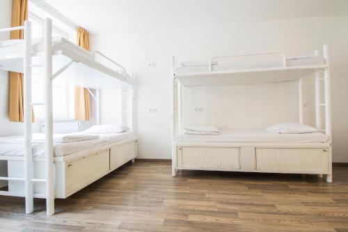 two bunk beds in a white room with wooden floors at Safestay Prague Charles Bridge in Prague