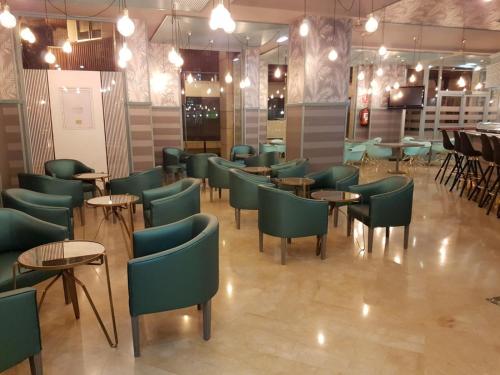 a restaurant with green chairs and tables and lights at Silken Reino de Aragón in Zaragoza