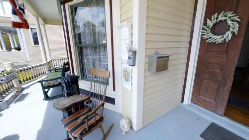 a porch with a wooden door and a rocking chair at Hanna House Bed & Breakfast in New Bern