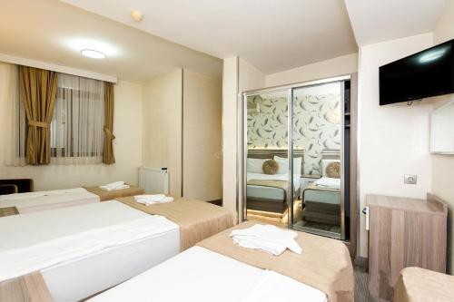 a hotel room with two beds and a flat screen tv at Olimpiyat Hotel Izmir in Izmir