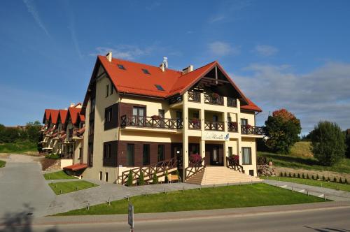 a large house with a red roof at Hotel Santa Monica in Mikołajki