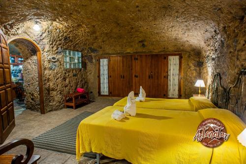 a bedroom with a yellow bed in a stone room at Casa Cueva El Mimo in Artenara