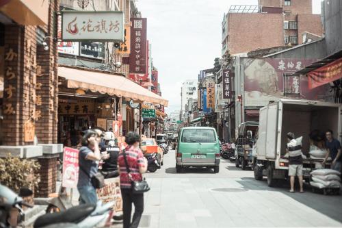a busy city street with a green van driving down the street at We Come Hostel in Taipei