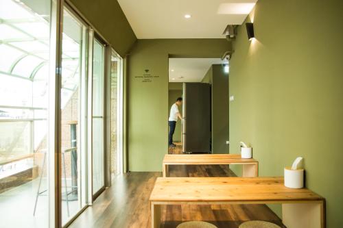 a man standing in a room with green walls at We Come Hostel in Taipei