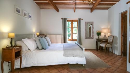 a bedroom with a large white bed and a desk at La Ferme Des Belugues in Le Barroux