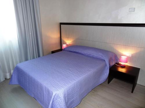 a bedroom with a bed and two lamps on tables at La Casa Degli Angeli - Agli Angeli Ristorante Pizzeria in Pertegada