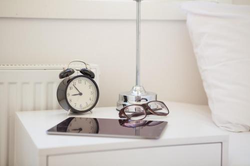 a clock and glasses sitting on top of a table at BJØRVIKA APARTMENTS, Teaterplassen, Oslo city center in Oslo