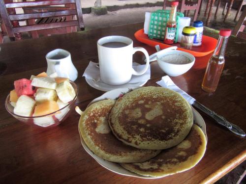 a table with a plate of pancakes and a cup of coffee at Caballito's Mar in Ometepe