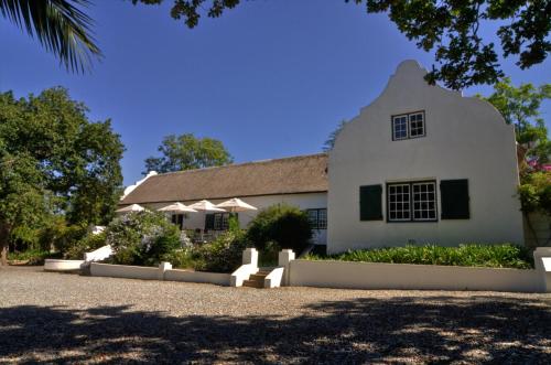 a large white building with a roof at De Kloof Heritage Estate and Wellness in Swellendam