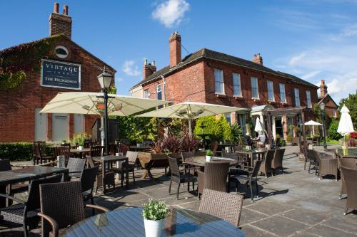 an outdoor restaurant with tables and chairs and umbrellas at The Hedgehog by Innkeeper's Collection in Lichfield