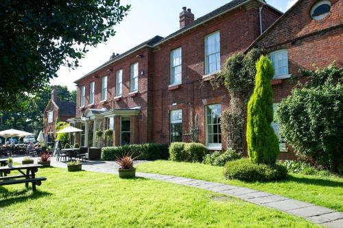 a large red brick building with a grass yard at The Hedgehog by Innkeeper's Collection in Lichfield