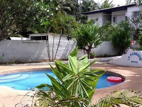 a swimming pool with a red frisbee next to a house at Hotel La Madrague in Grand-Bassam