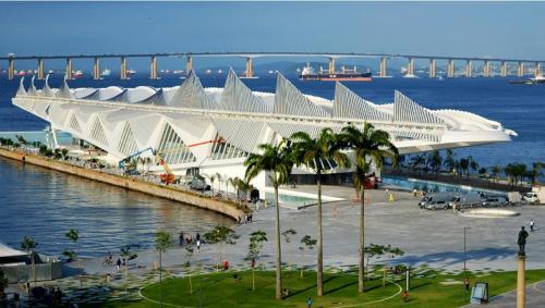 a large white building with a bridge in the background at Hotel La Costa - Adults Only in Rio de Janeiro