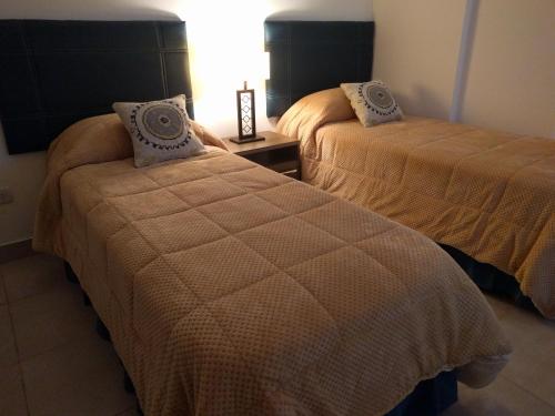 1 dormitorio con 2 camas con edredones marrones en Magallanes en Ushuaia