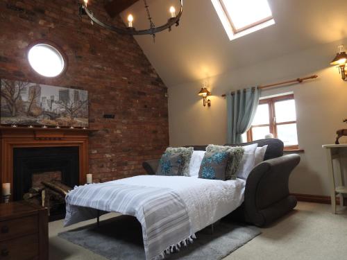 a bedroom with a bed and a brick wall at Pillory House Loft Apartment in Nantwich