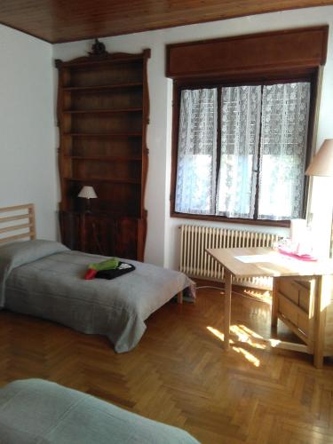 a bedroom with two beds and a table and a window at Ristoro 25 Aprile in Tolmezzo