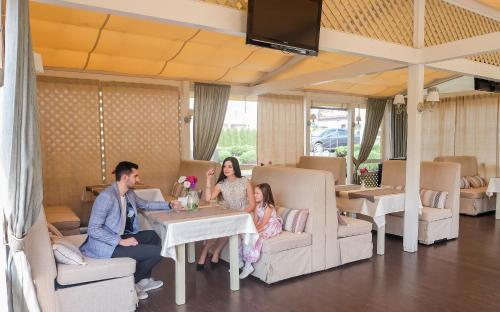 a family sitting at a table in a restaurant at Maria Garden hotel & restaurant in Ivano-Frankivsʼk